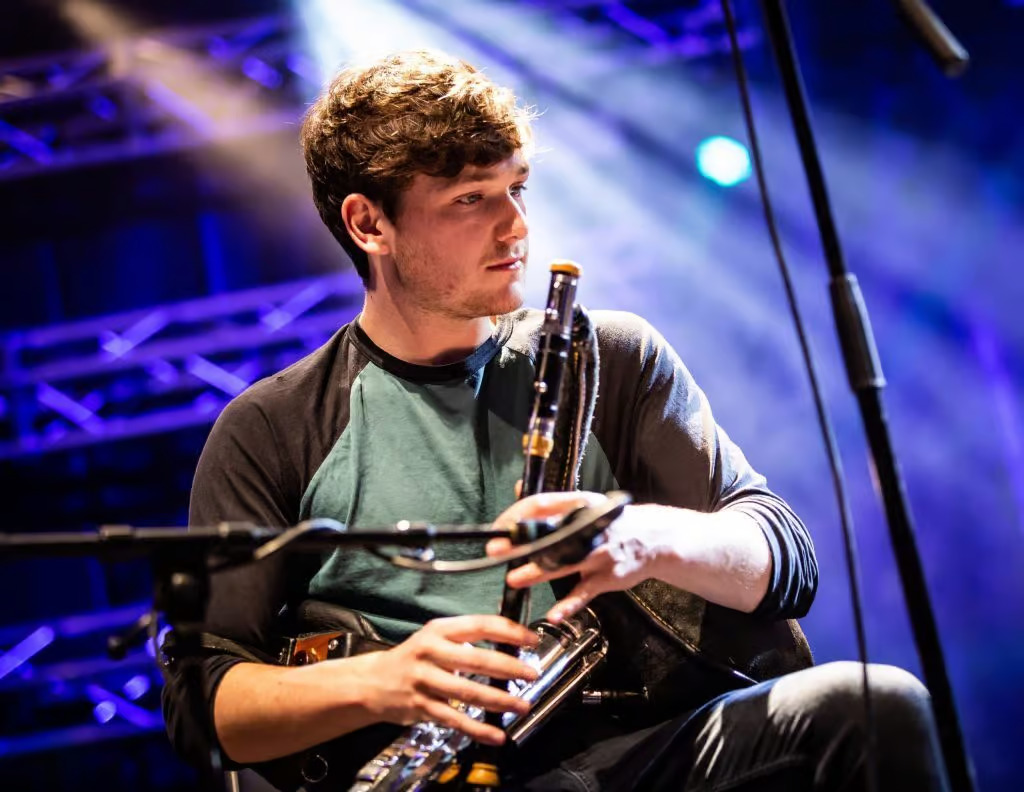 Conal McDonagh playing pipes on stage, lit up in blue stage lighting