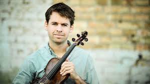 Kevin Lees holding his fiddle, smiling at the camera