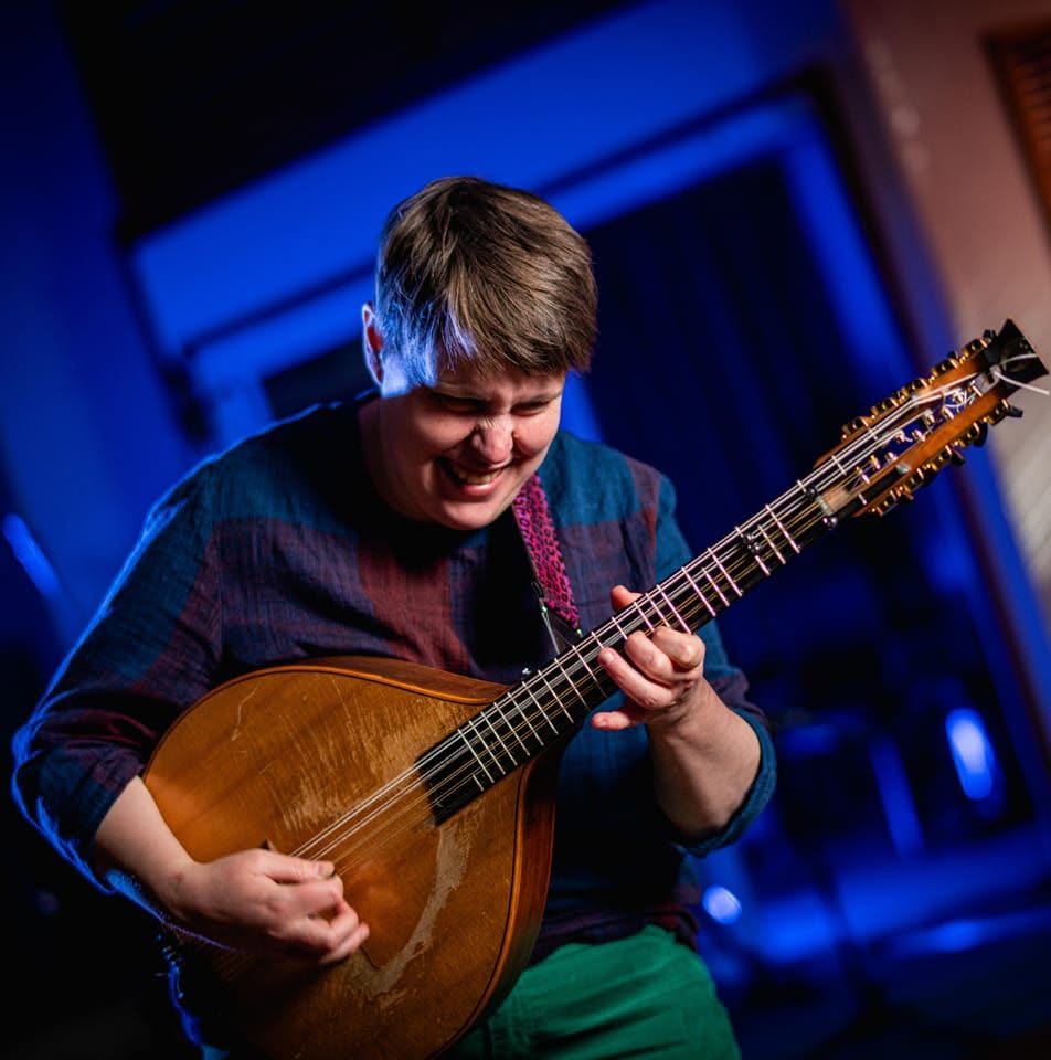 Marit Fält laughing as she plays her Låtmandola on stage